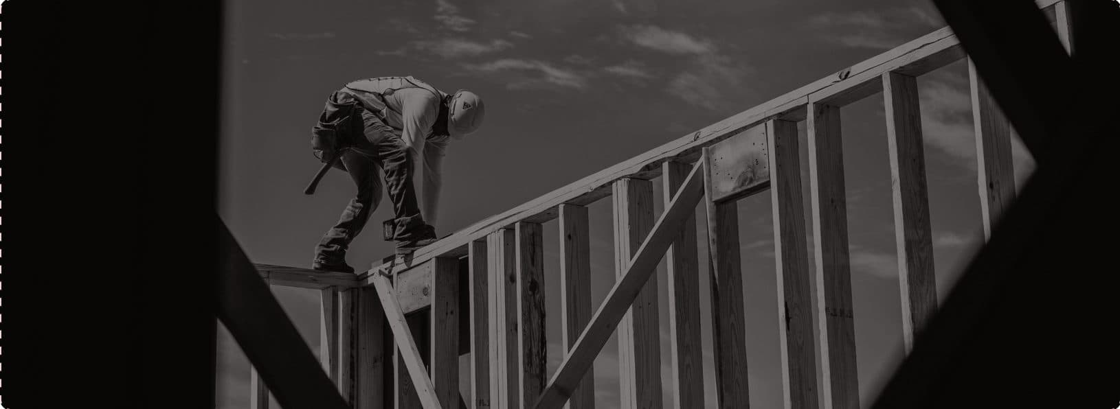 A framer working on a timber staircase against an open sky