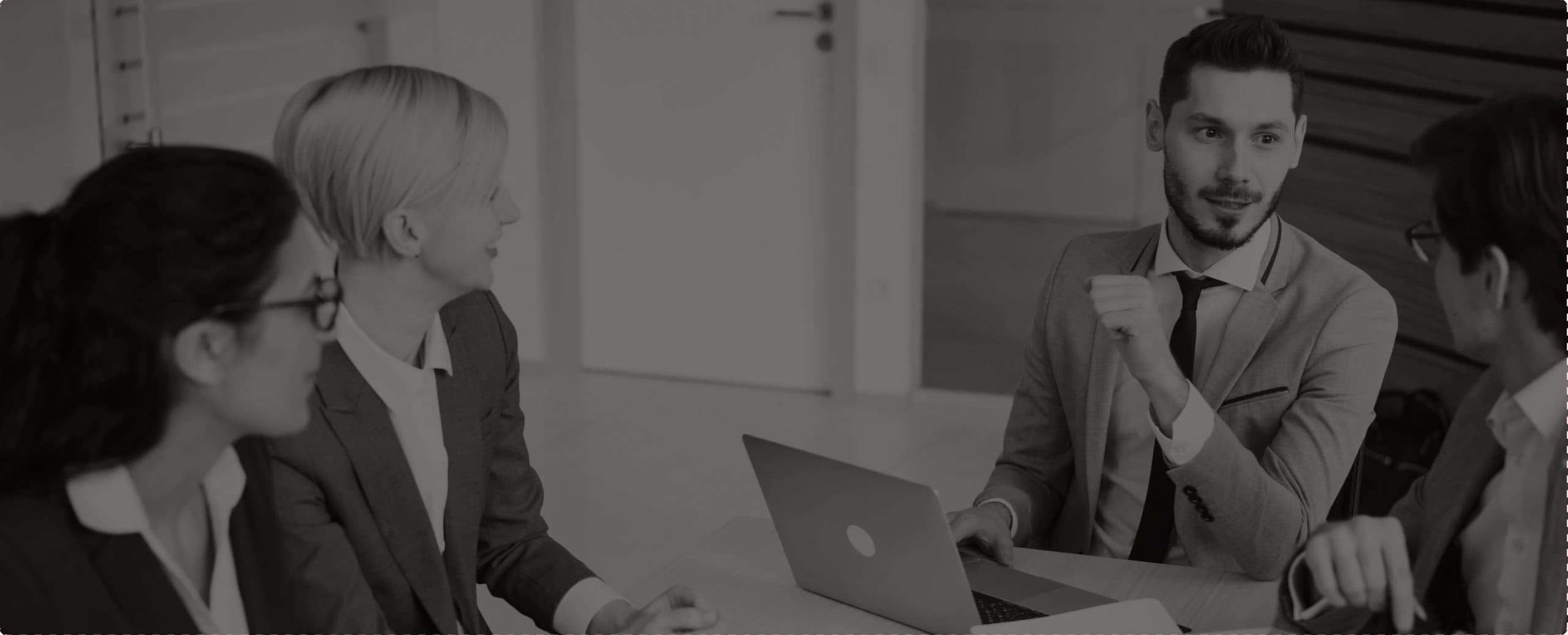 An agent listening in a meeting with colleagues around a laptop